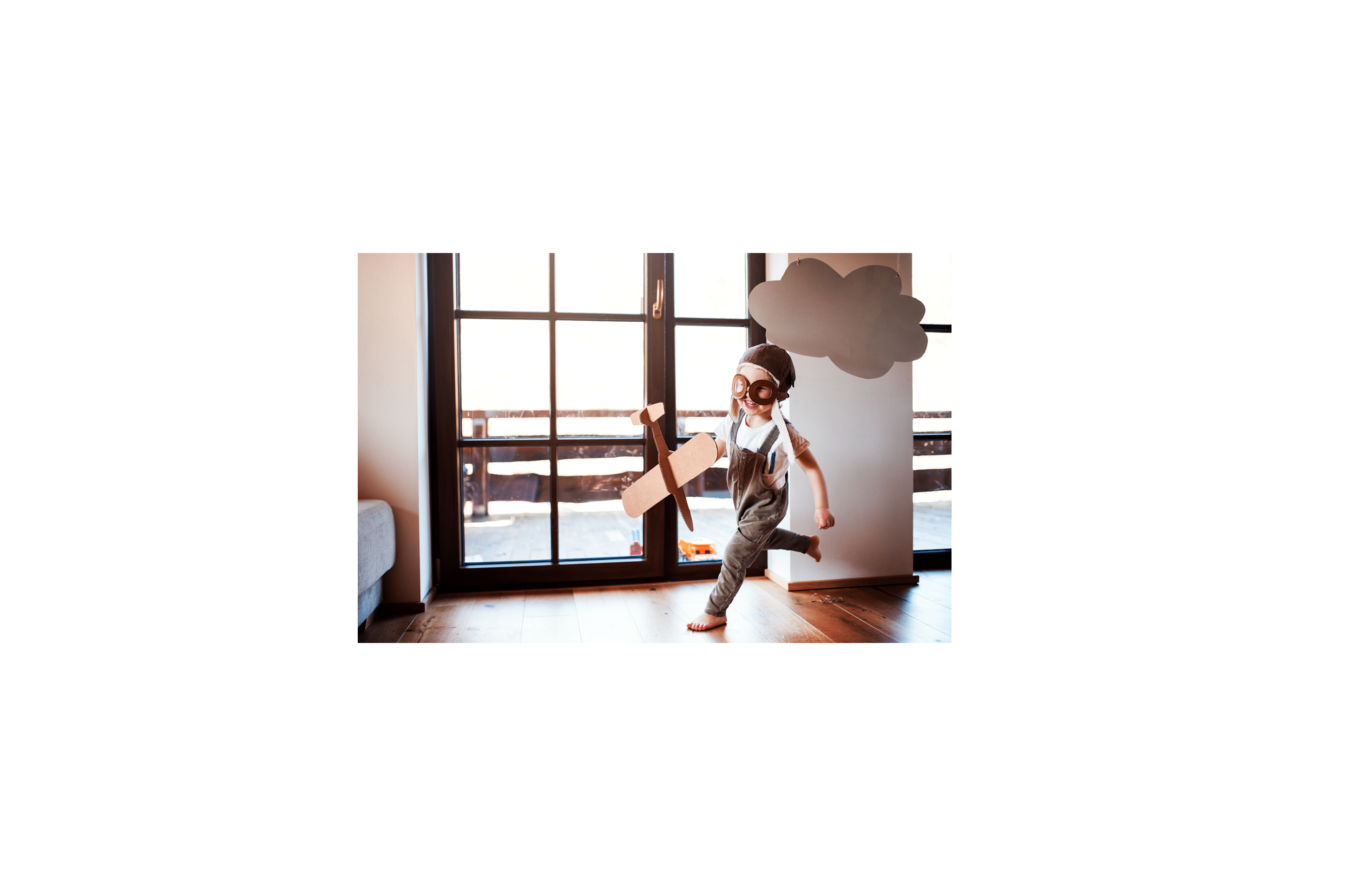 A toddler boy with carton plane and clouds playing indoors at home, flying concept.