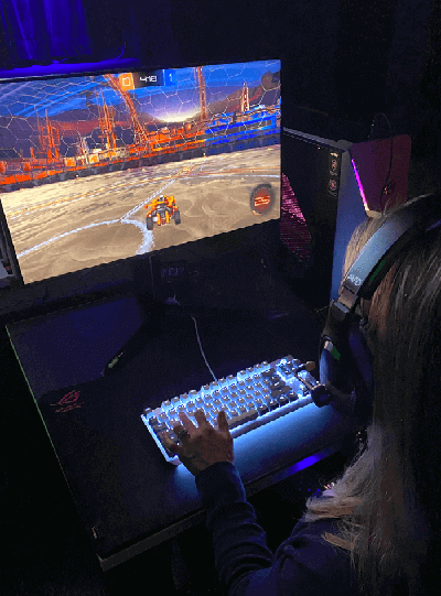Young adult wearing AVID AE-79 USB Headset and gaming on a desktop computer.